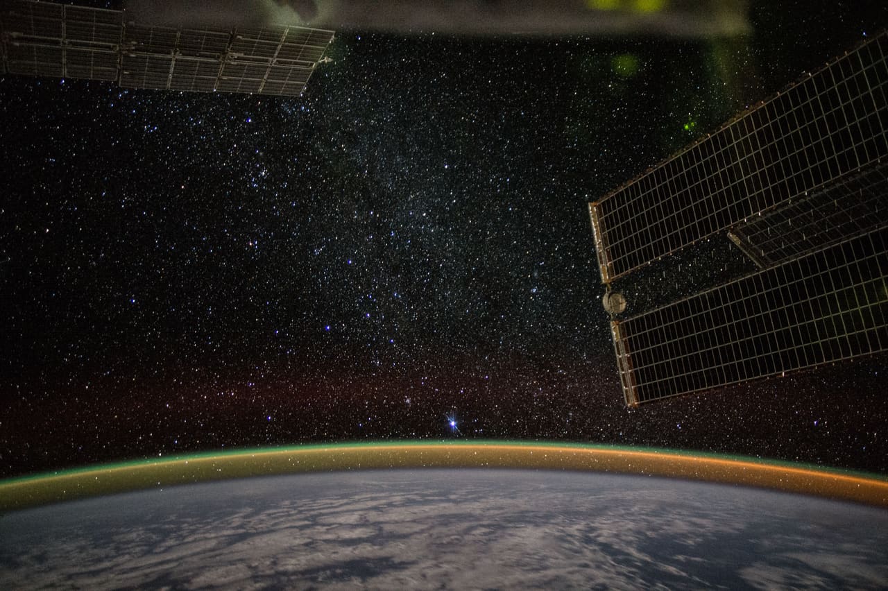 Earth's atmosphere glowing as a thin band above the planet on a night pass from orbit