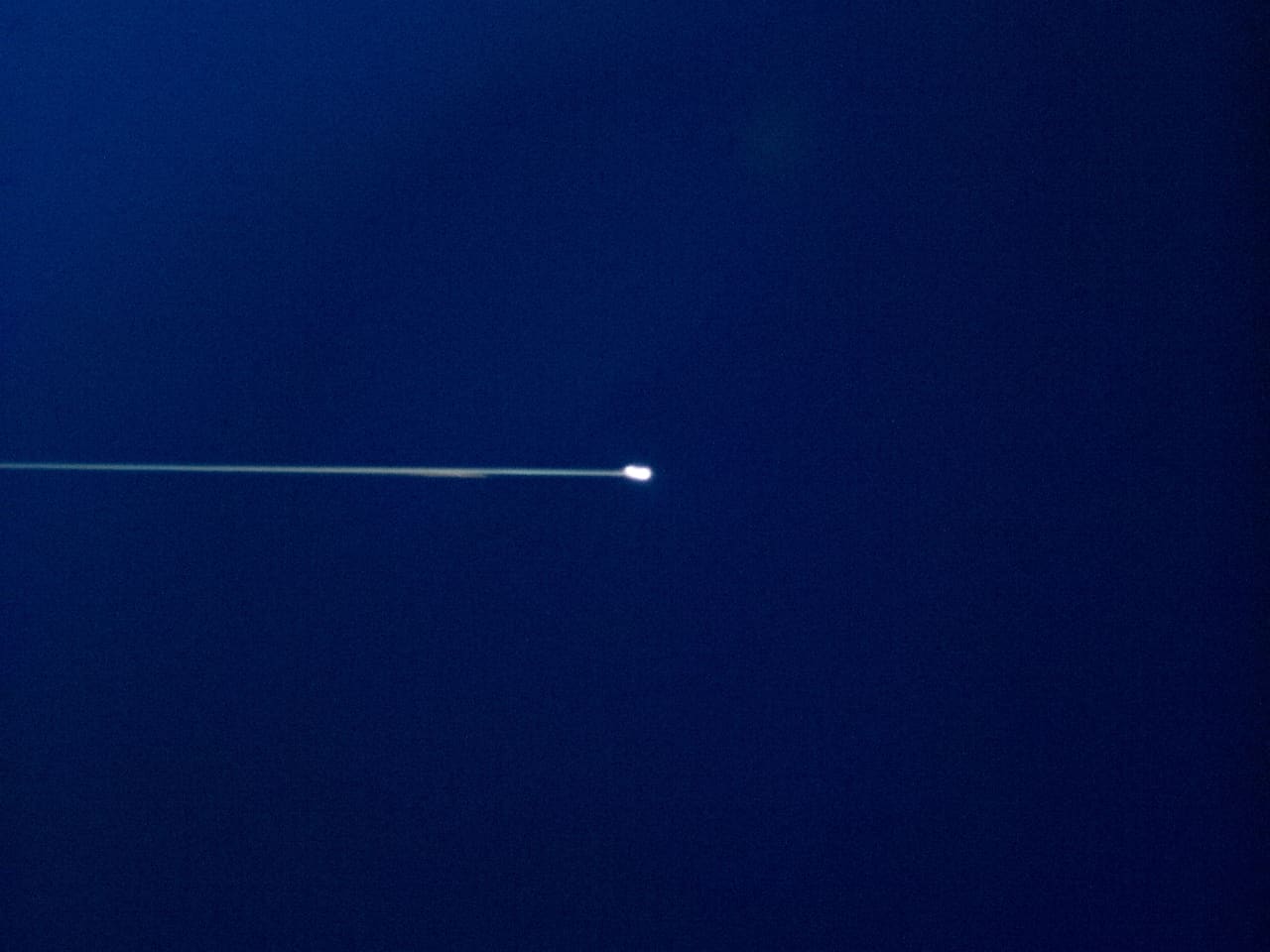 A spacecraft breaking into glowing fragments during atmospheric reentry, photographed from above
